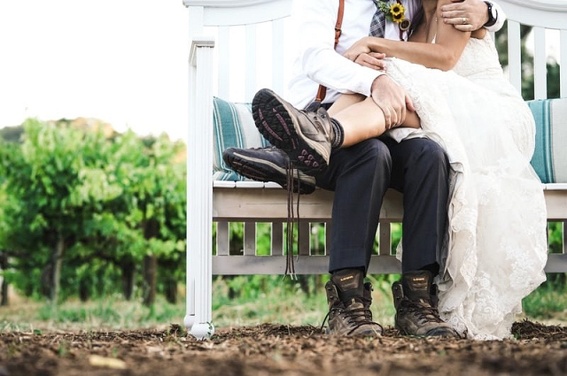 34 of the Best Wedding Gifts for Wine Lovers, a couple sitting on a patio bench. The woman is in a wedding dress, signifying the couple was just married.